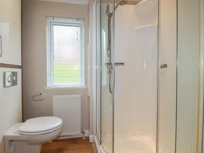 a bathroom with a toilet and a glass shower at Haven Lodge in Tintagel