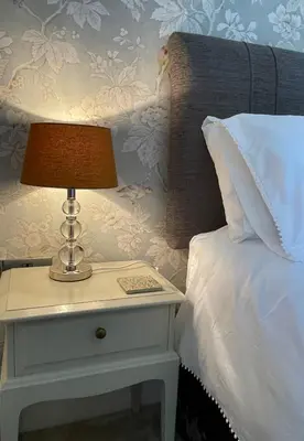 a bed with a lamp on a night stand next to a bed at Treveighan Farmhouse in Saint Teath