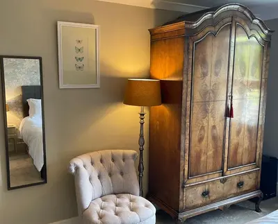 a bedroom with a large wooden cabinet and a chair at Treveighan Farmhouse in Saint Teath