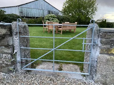 a gate to a garden with a table and chairs at Treveighan Farmhouse in Saint Teath