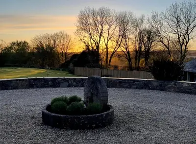 a garden with a bush in a gravel yard at Treveighan Farmhouse in Saint Teath