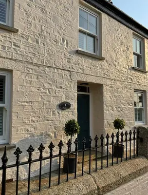 a black fence in front of a building with a door at Treveighan Farmhouse in Saint Teath