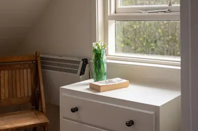 a vase on top of a dresser next to a window at The Sail Loft (part of Manor House) in Port Isaac