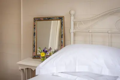 a bedroom with a white bed and a mirror at The Sail Loft (part of Manor House) in Port Isaac