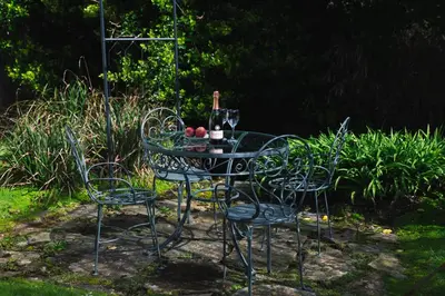 a glass table with four chairs and a bottle of wine at The Sail Loft (part of Manor House) in Port Isaac