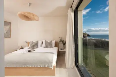 a bedroom with a bed and a view of the ocean at Little Cottage and Love Shack in Praa Sands