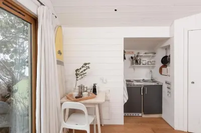 a kitchen with white walls and a table and chairs at Little Cottage and Love Shack in Praa Sands