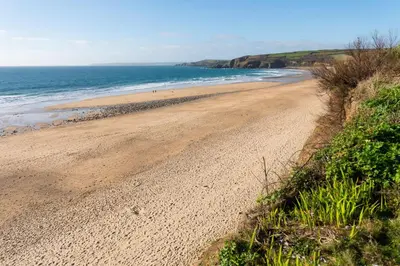 a sandy beach next to the ocean on a sunny day at Little Cottage and Love Shack in Praa Sands