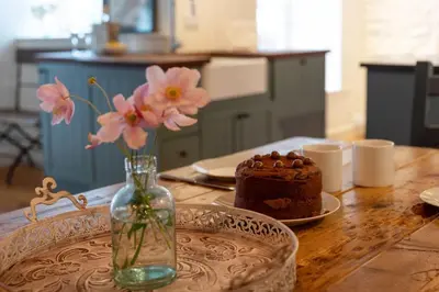 a table with a vase with flowers and a cake at The Manor House in Port Isaac