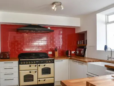 a kitchen with a stove and a red brick wall at Crantock House in Newquay