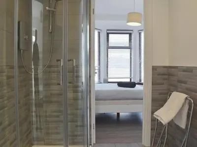 a bathroom with a shower and a bedroom with a bed at Crantock House in Newquay