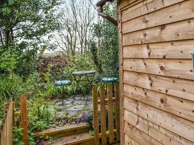 a wooden fence with a table in a garden at Field View in St Austell
