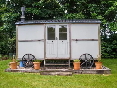 a white shed with two large wheels in a yard at Garden Studio in St Austell