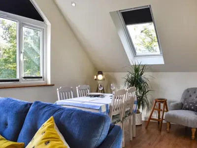 a living room with a blue couch and a table at Garden Studio in St Austell