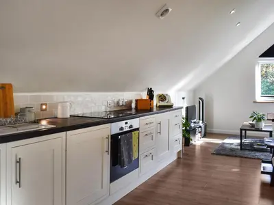 a kitchen with white cabinets and black counter tops at Garden Studio in St Austell