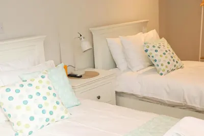 a bedroom with two beds with pillows and a lamp at Stylish estuary view apartment in Padstow
