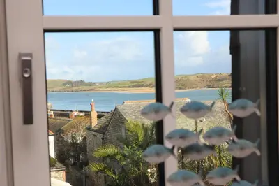 a window with a view of a beach and the ocean at Stylish estuary view apartment in Padstow