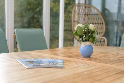 a blue vase with flowers on a wooden table at Stunning River Views, Tranquil Split-Level House, Private Garden & Parking in Golant