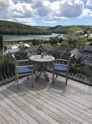 a table and chairs on a deck with a view of a river at Stunning River Views, Tranquil Split-Level House, Private Garden & Parking in Golant