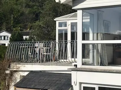 a balcony of a white house with a railing at Stunning River Views, Tranquil Split-Level House, Private Garden & Parking in Golant