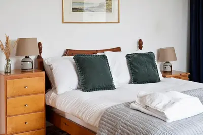 a bedroom with a bed with green and white pillows at Beautiful Cornish Home 