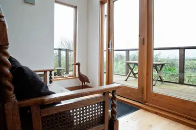 a room with a bird sitting on a bench next to windows at Beautiful Cornish Home 