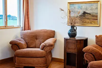 a living room with a chair and a vase on a table at Beautiful Cornish Home 