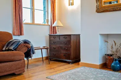 a living room with a chair and a dresser at Beautiful Cornish Home 