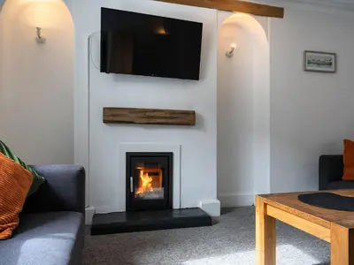 a living room with a fireplace with a tv on the wall at Ayr Farmhouse in St Ives