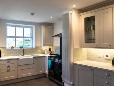 a kitchen with white cabinets and a sink and a stove at Ayr Farmhouse in St Ives
