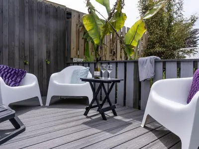 a patio with white chairs and a table on a wooden deck at Ayr Farmhouse in St Ives