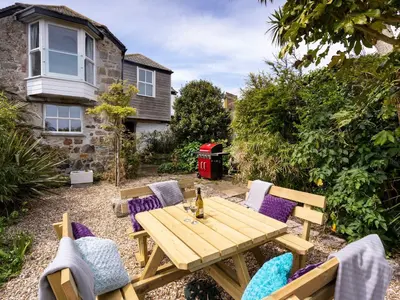 a wooden table and chairs in a garden at Ayr Farmhouse in St Ives