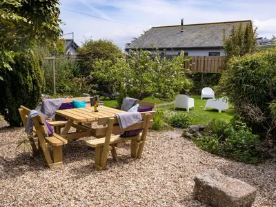 a wooden table and chairs in a garden at Ayr Farmhouse in St Ives