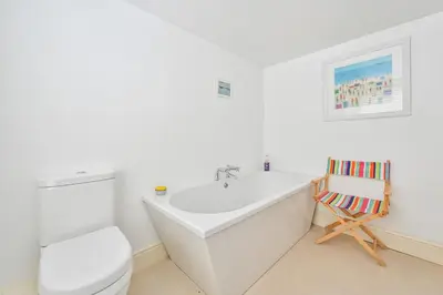 a white bathroom with a toilet and a bath tub at Captain's House Looe in Looe