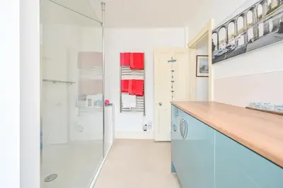 a bathroom with a shower and a blue cabinet at Captain's House Looe in Looe