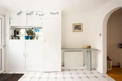 a kitchen with white cabinets and a table at Hibiscus house in Newquay