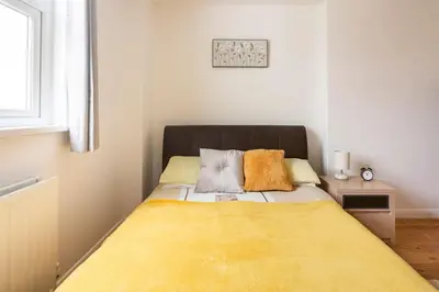a bedroom with a bed with a yellow blanket at Hibiscus house in Newquay