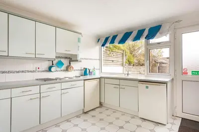 a white kitchen with white cabinets and a window at Hibiscus house in Newquay