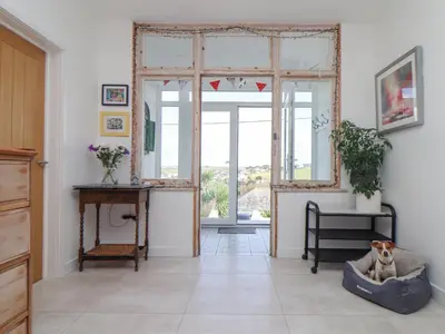 a living room with a large window and a dog in a bed at Higher Bolenna in Perranporth