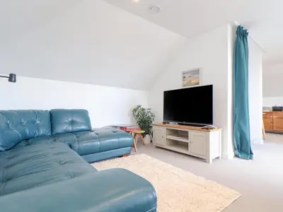 a living room with a blue couch and a flat screen tv at Higher Bolenna in Perranporth