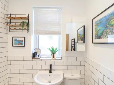 a white bathroom with a sink and a window at Higher Bolenna in Perranporth