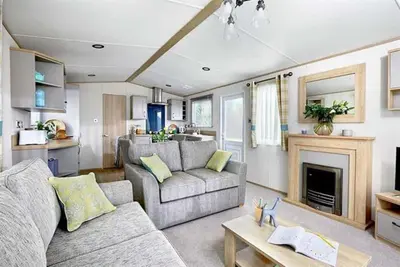 a living room with a couch and a fireplace at Cornwall Holiday Cabin with Hot tub & Sea view in Cubert