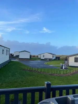 a view of a yard with houses and a fence at Cornwall Holiday Cabin with Hot tub & Sea view in Cubert