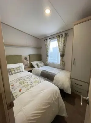 a small bedroom with two beds and a window at Cornwall Holiday Cabin with Hot tub & Sea view in Cubert