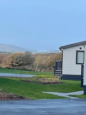a building with a sign next to a road at Cornwall Holiday Cabin with Hot tub & Sea view in Cubert