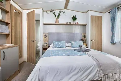 a bedroom with a large bed with blue pillows at Cornwall Holiday Cabin with Hot tub & Sea view in Cubert