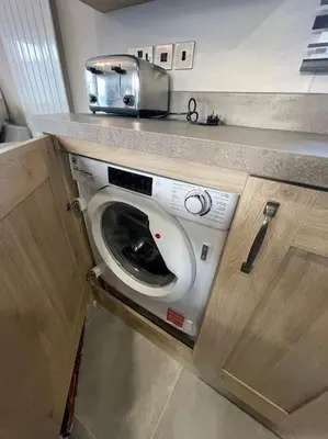 a washing machine under a counter in a kitchen at Cornwall Holiday Cabin with Hot tub & Sea view in Cubert