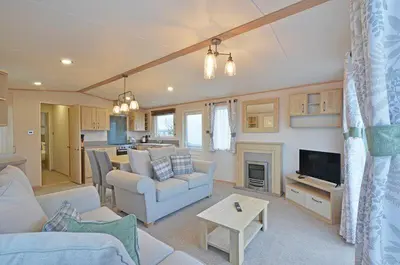 a living room with a couch and a tv and a kitchen at Cornwall Holiday Cabin with Hot tub & Sea view in Cubert