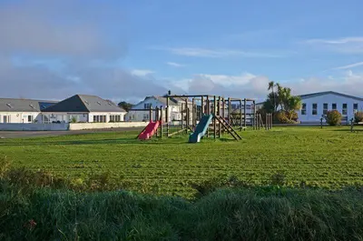 a park with a playground with a slide in a field at Cornwall Holiday Cabin with Hot tub & Sea view in Cubert