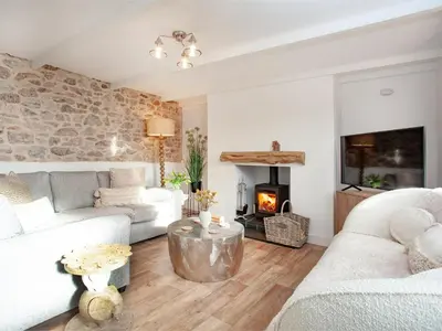 a living room with a couch and a fireplace at Harlequin Cottage in St Austell